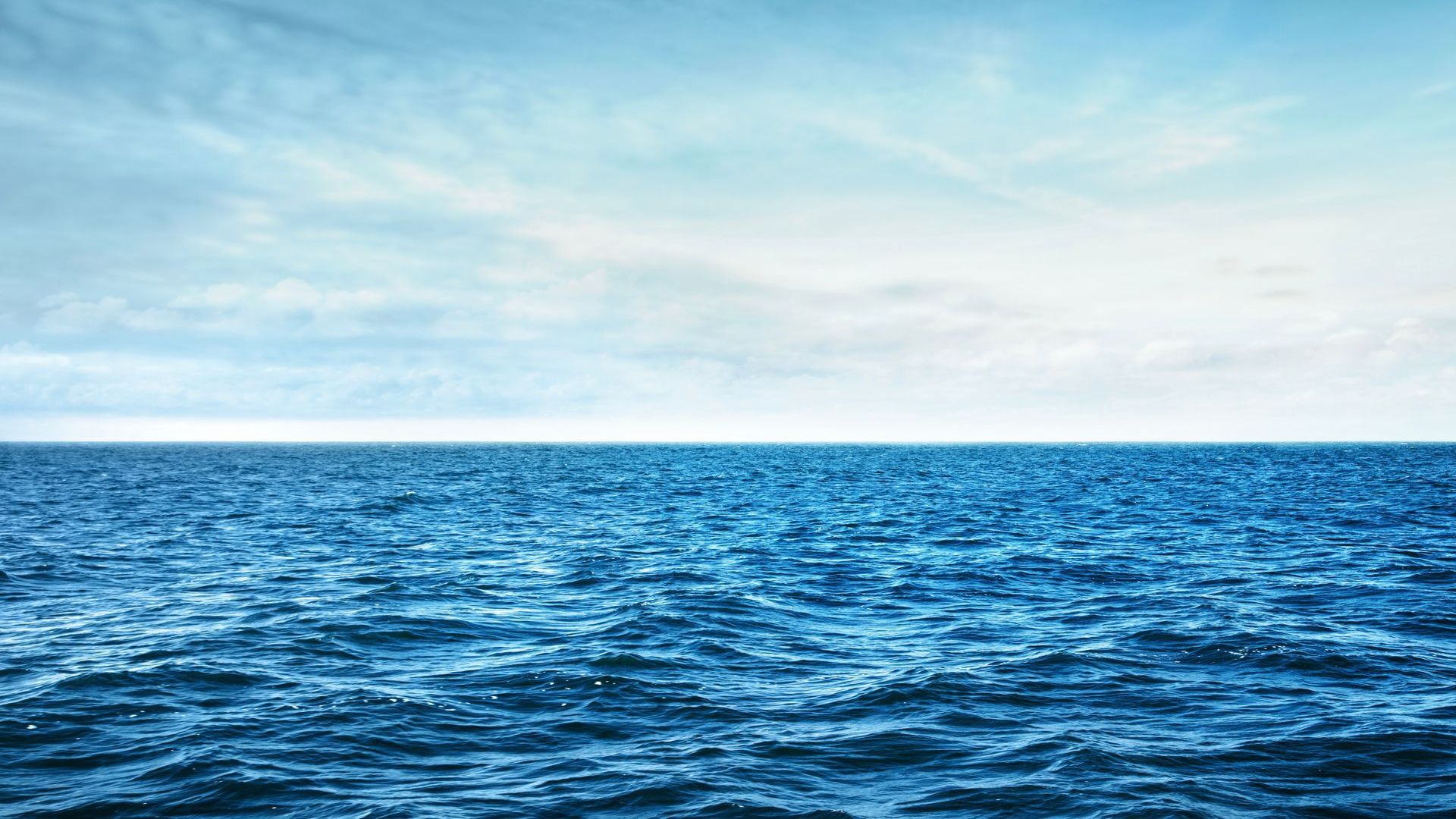 A large body of water with waves and a blue sky in the background.