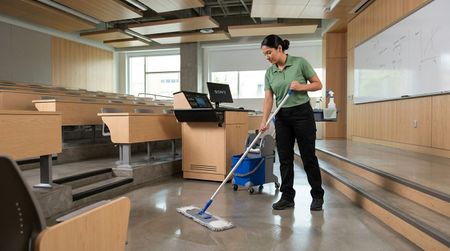 Cleaner mopping and cleaning lecture hall floors and front teaching area Edina, MN