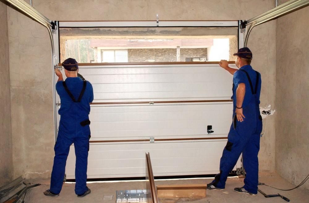 Two men are installing a garage door in a garage.