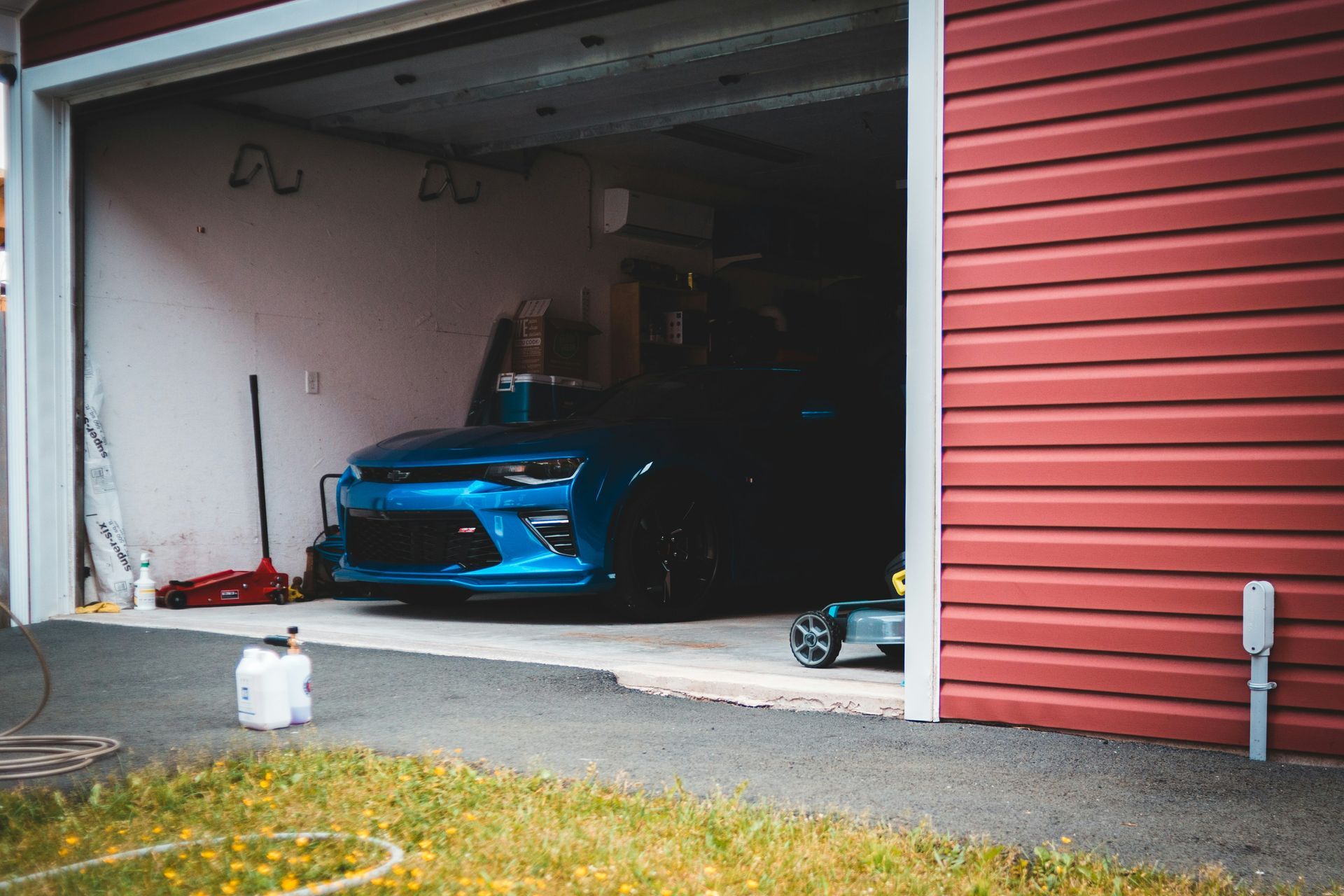 A blue car is parked in a garage with the door open.