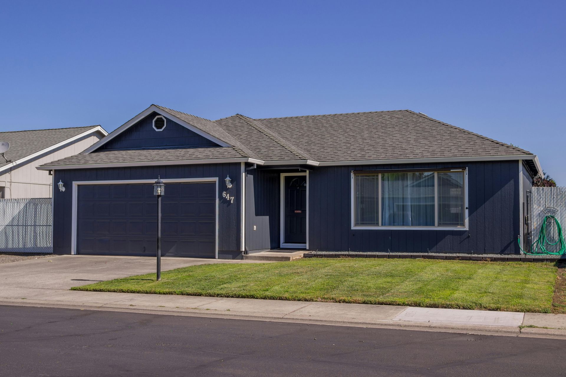 A black house with a garage and a blue sky in the background