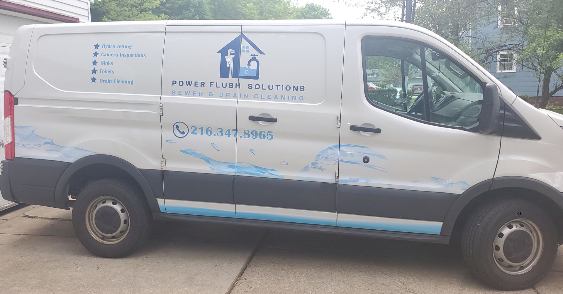 A white van with a house on the side is parked in a driveway.