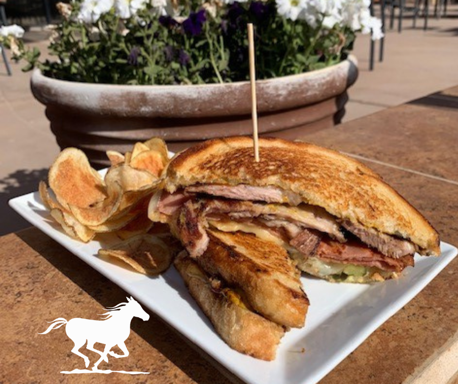 A sandwich with a toothpick in it is on a plate with chips