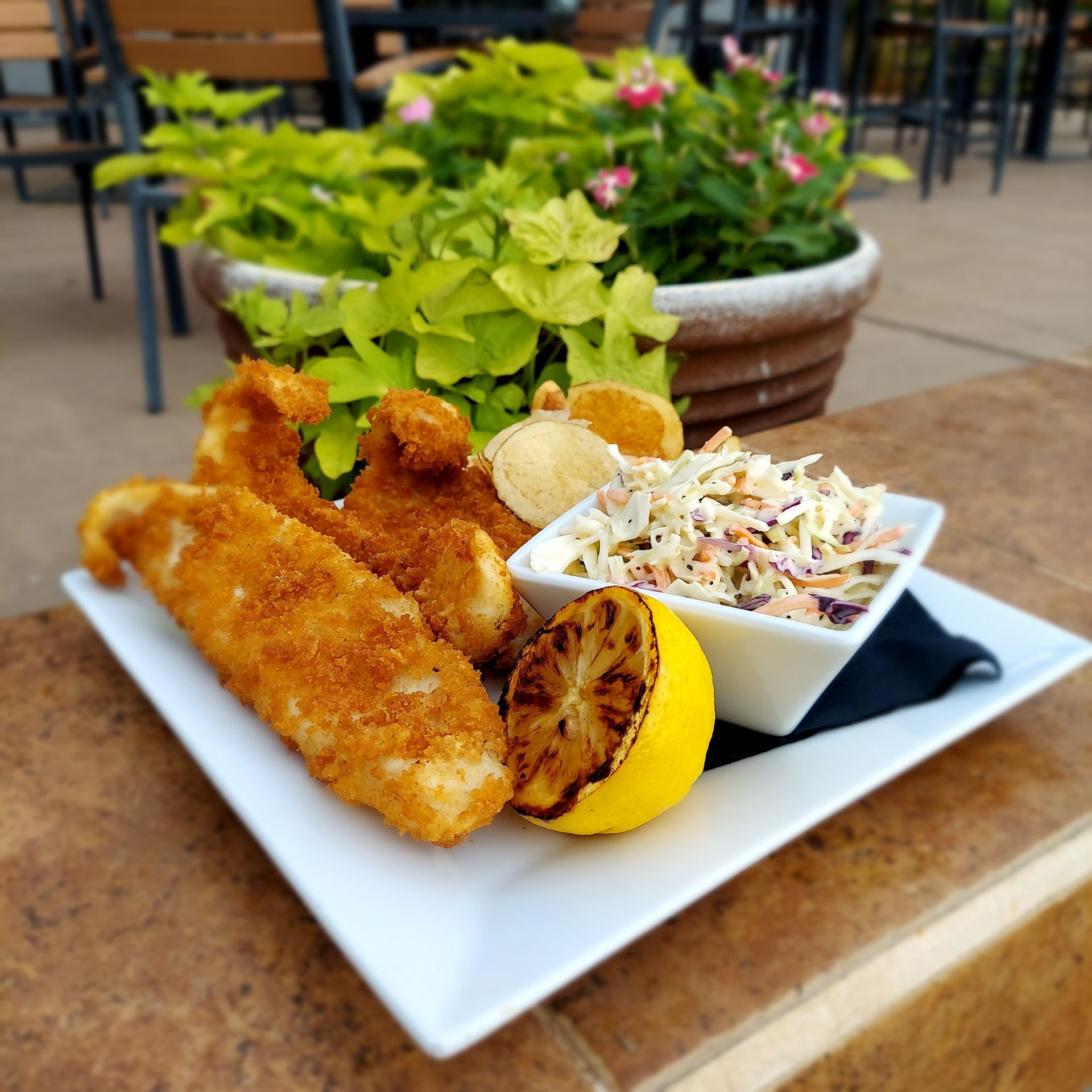 A white plate topped with fried fish and coleslaw