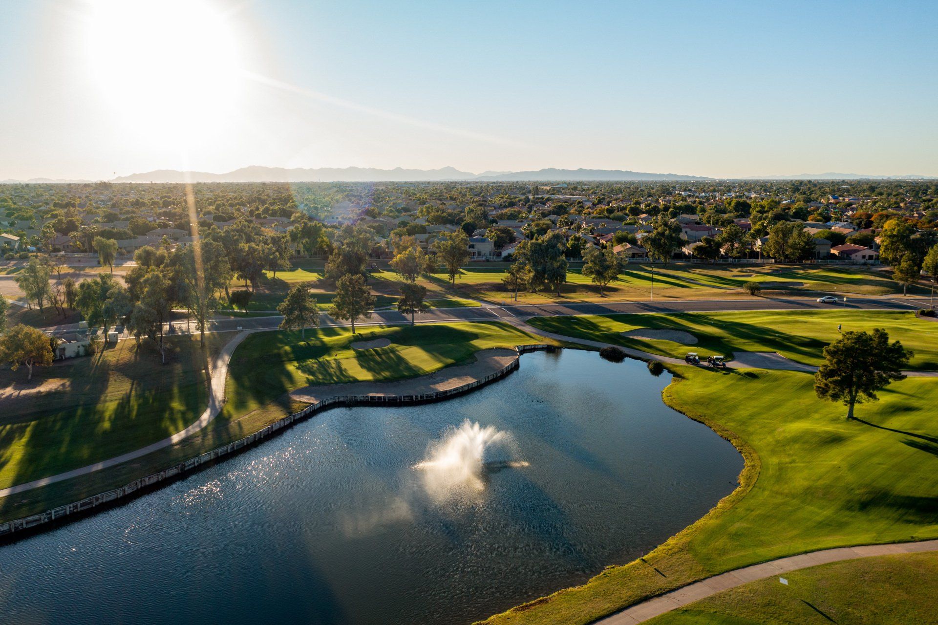 An aerial view of a golf course with a fountain in the middle of the lake.