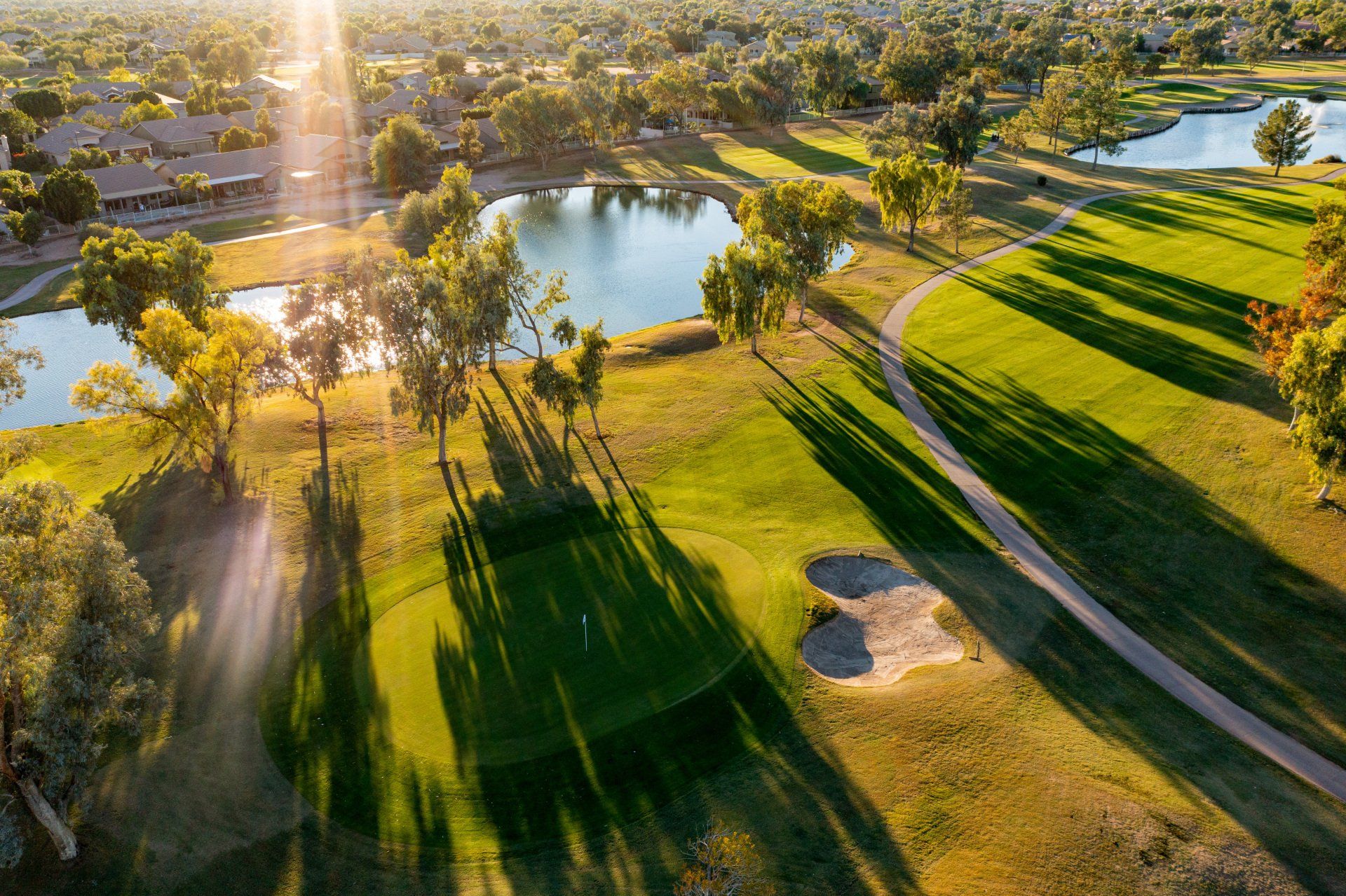 An aerial view of a golf course with trees and a lake.