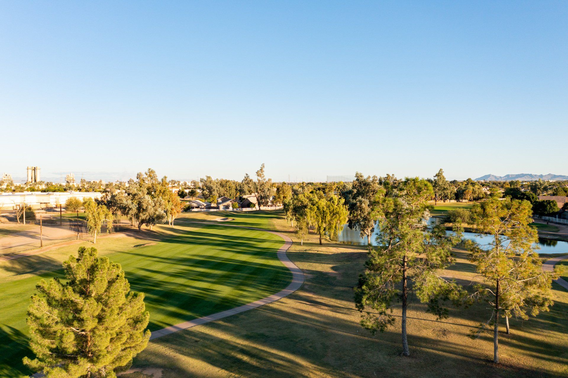 An aerial view of a golf course surrounded by trees and a lake.