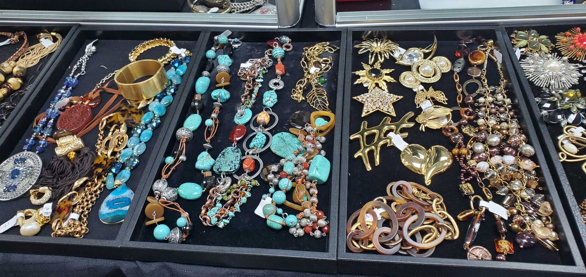 Jewelry display with necklaces, bracelets, and brooches in various colors and styles.