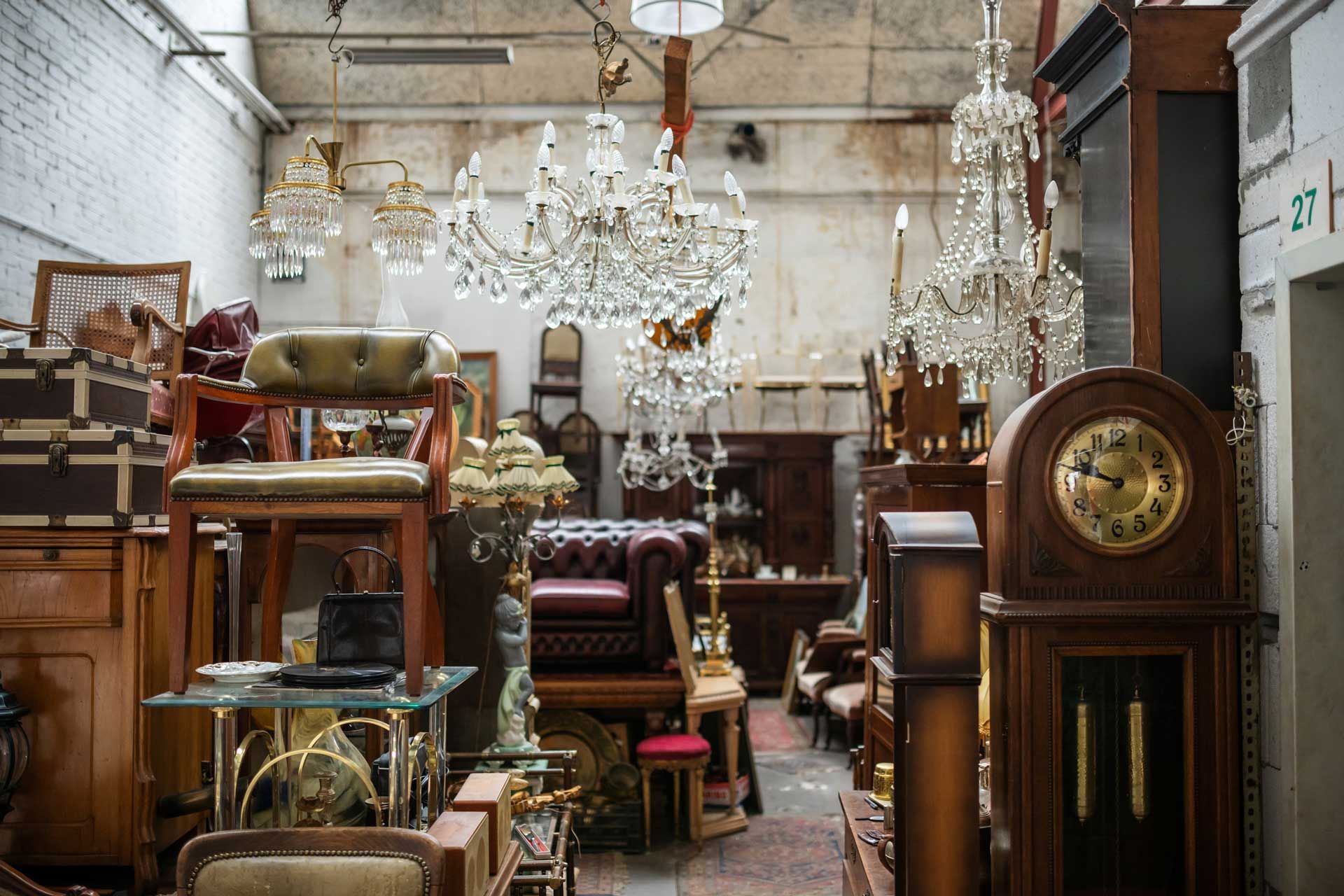 Antique shop interior filled with furniture, chandeliers, and decorative items.