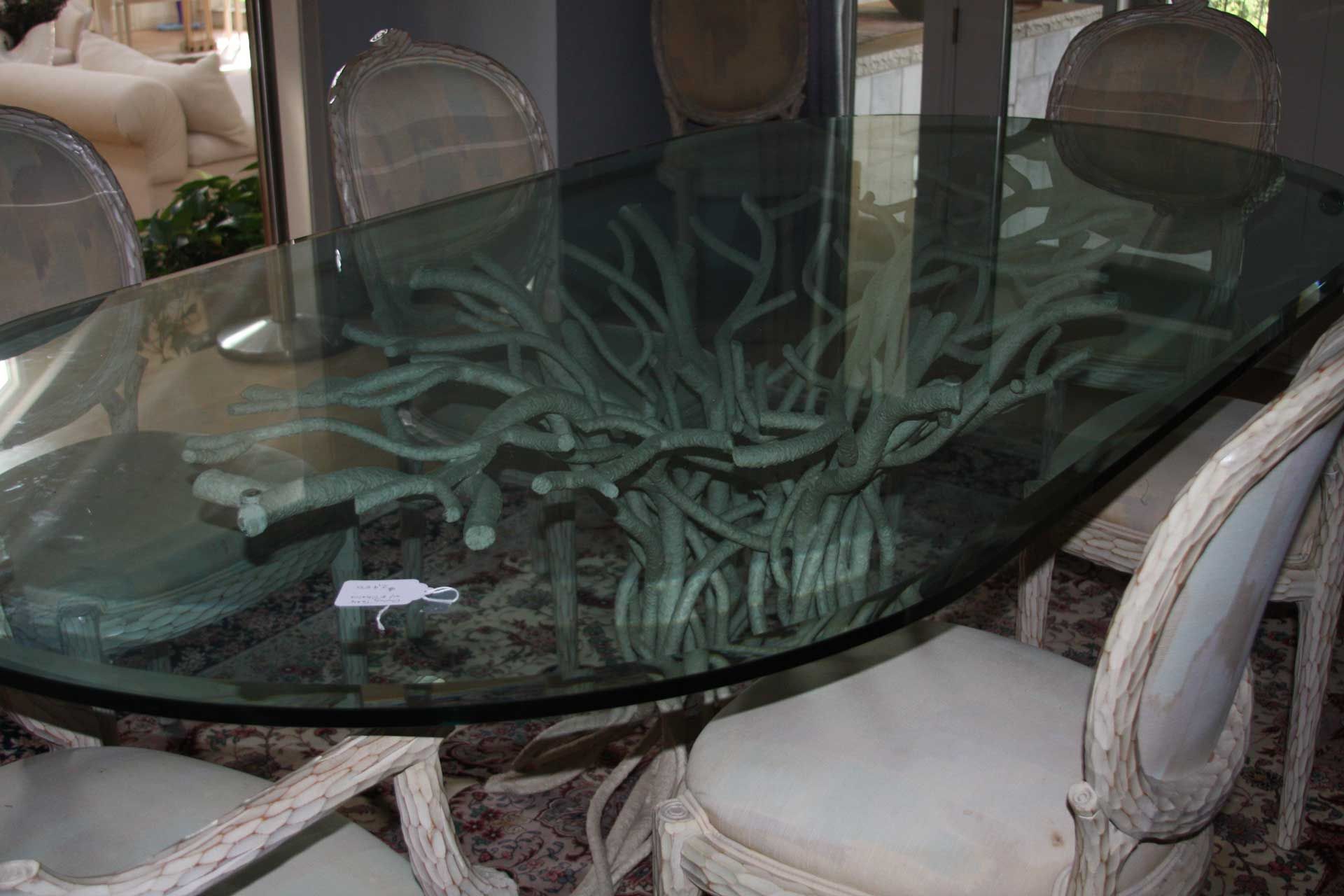 Glass dining table with a driftwood base, surrounded by white chairs.