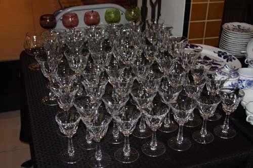 Arrangement of crystal wine glasses on a table. Additional decorative items are in the background.