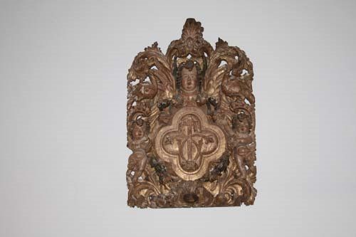Ornate, gilded wooden relief carving of a figure within foliate and floral designs.