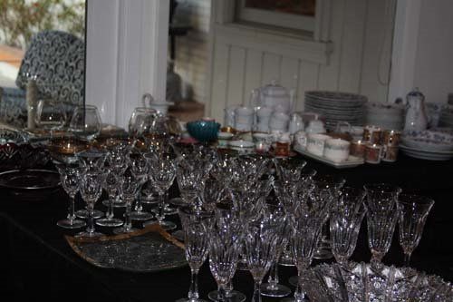 Close-up of a table displaying a large collection of crystal glassware and dishes, with a mirror in the background.