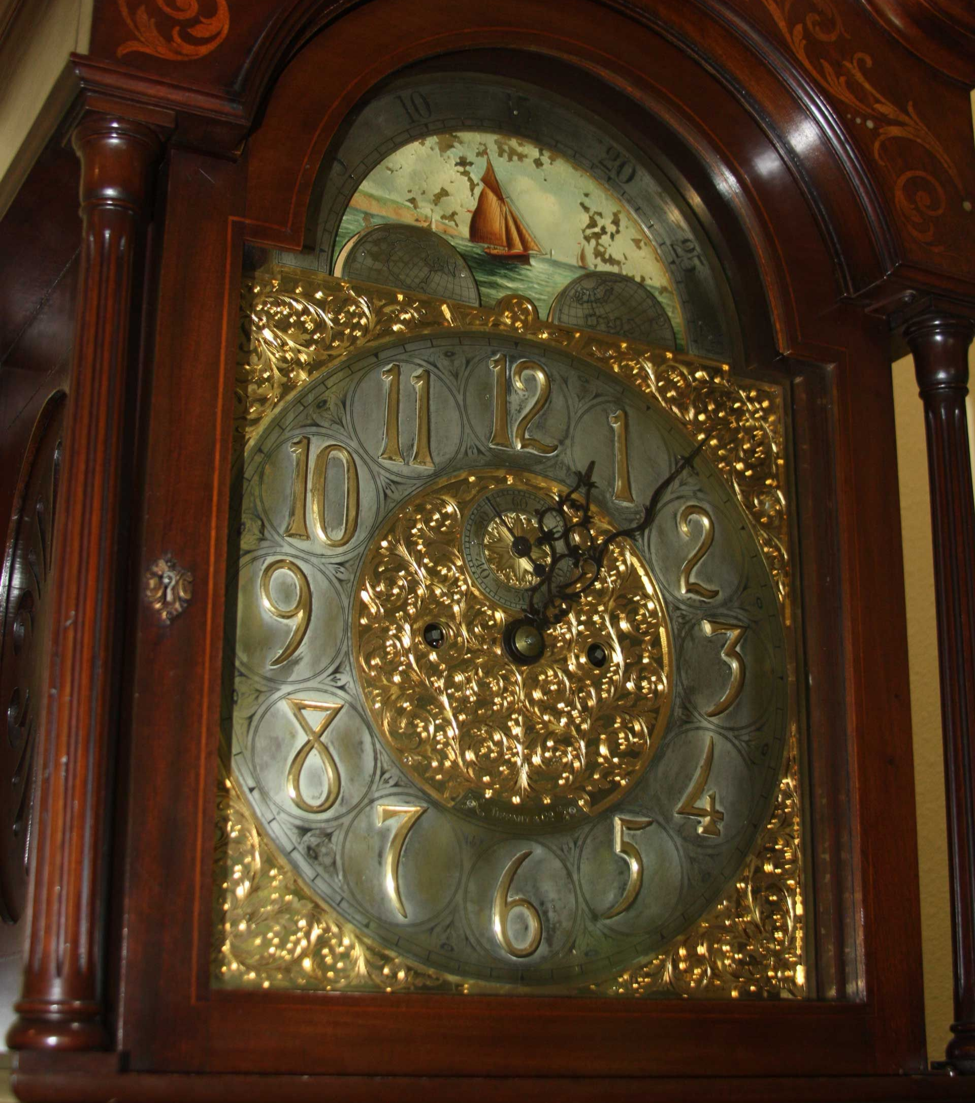 Bronze sculpture of a nude figure kneeling, arms outstretched, framed by green, vine-like structures, on a black marble base.