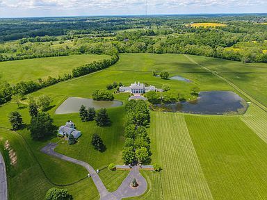 An aerial view of a large lush green field with a house in the middle.