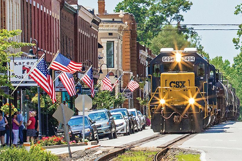 A train is going down the tracks in a small town.