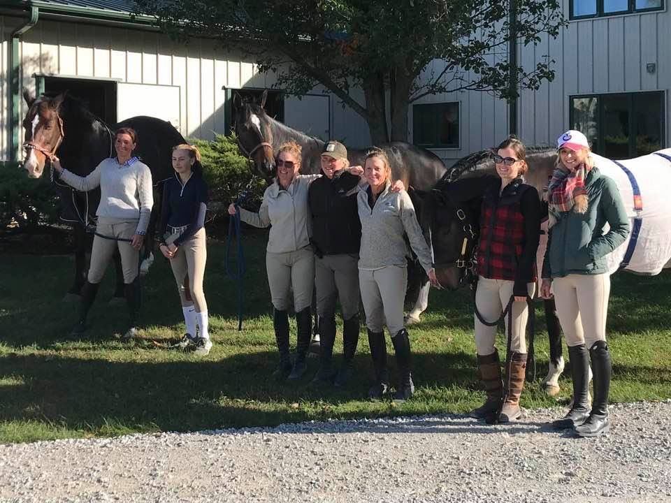 A group of people standing next to horses in front of a building