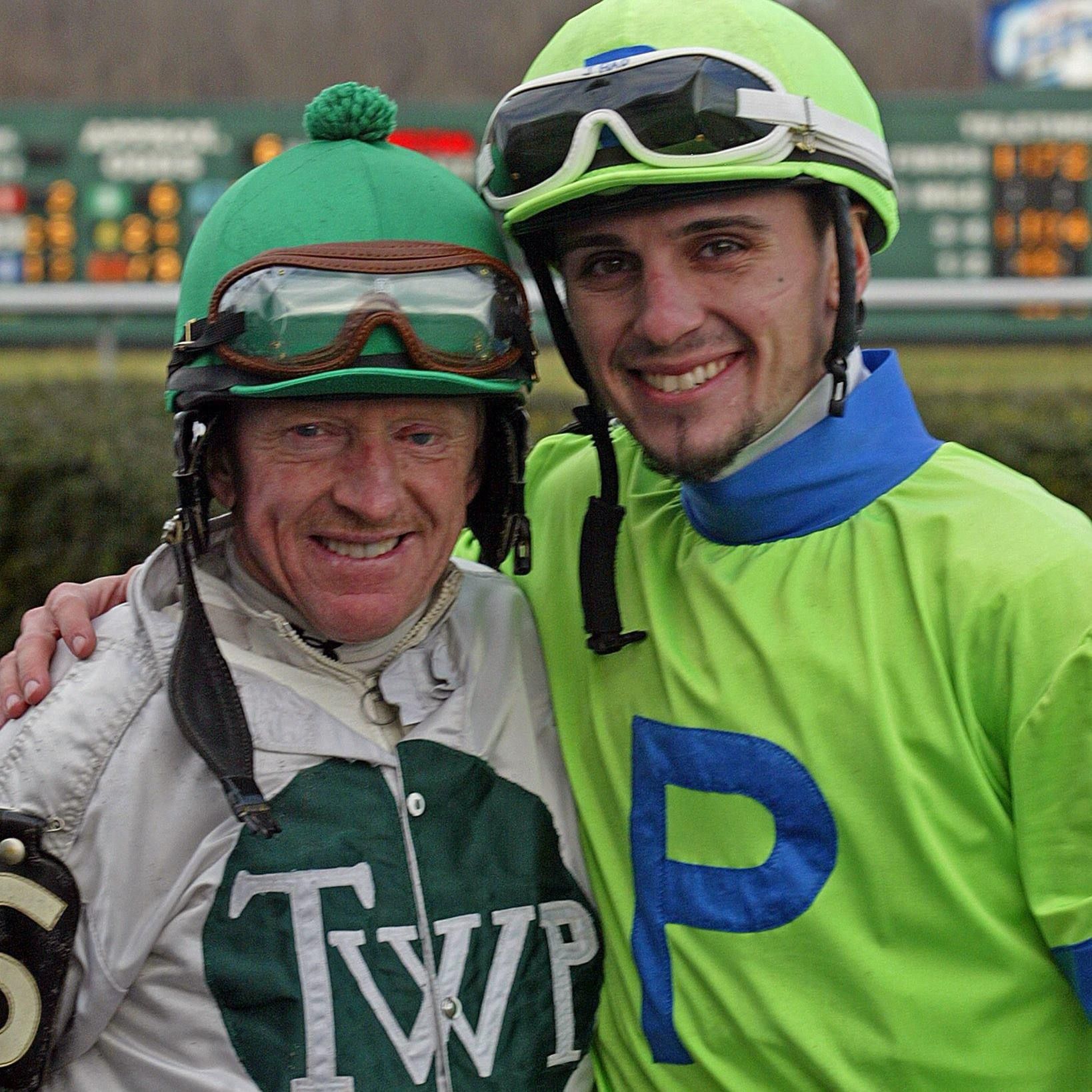 Two jockeys are posing for a picture and one is wearing a shirt that says twp