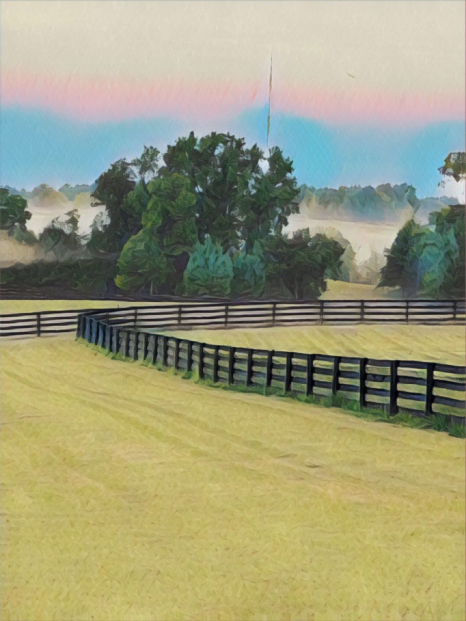 A fence surrounds a grassy field with trees in the background