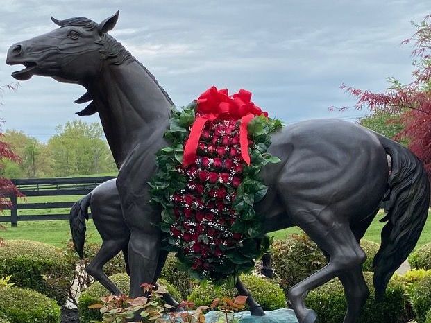 A statue of a horse with a wreath around its neck