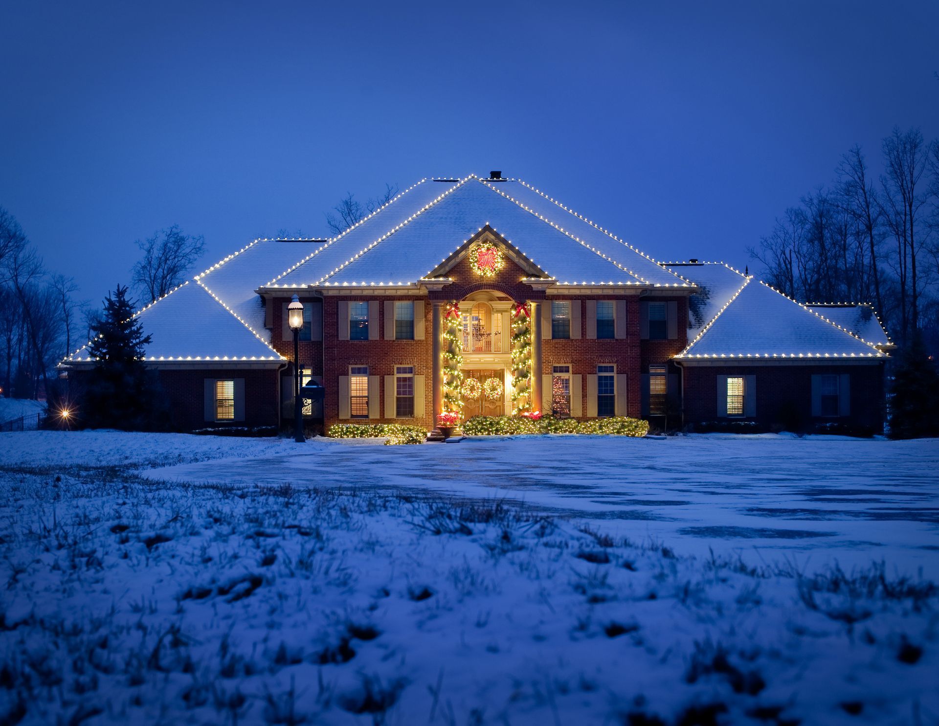 Snowy house at night, decorated with Christmas lights.