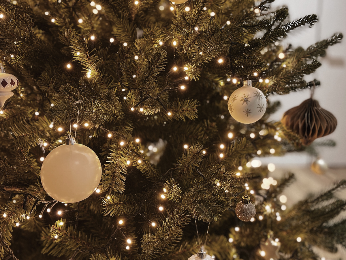 A close up of a christmas tree decorated with red balls and lights.