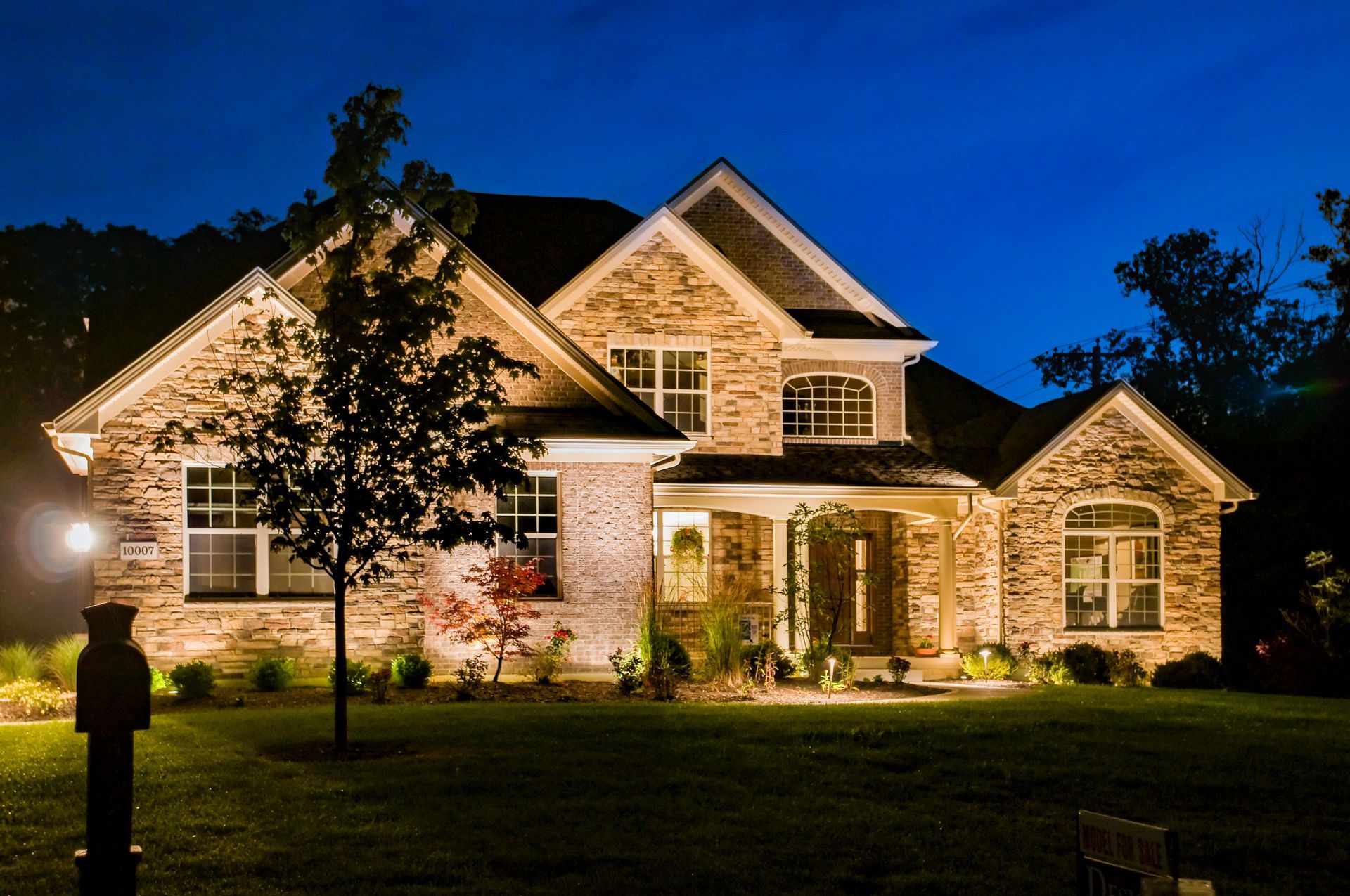Well-lit stone house at night with a dark blue sky.
