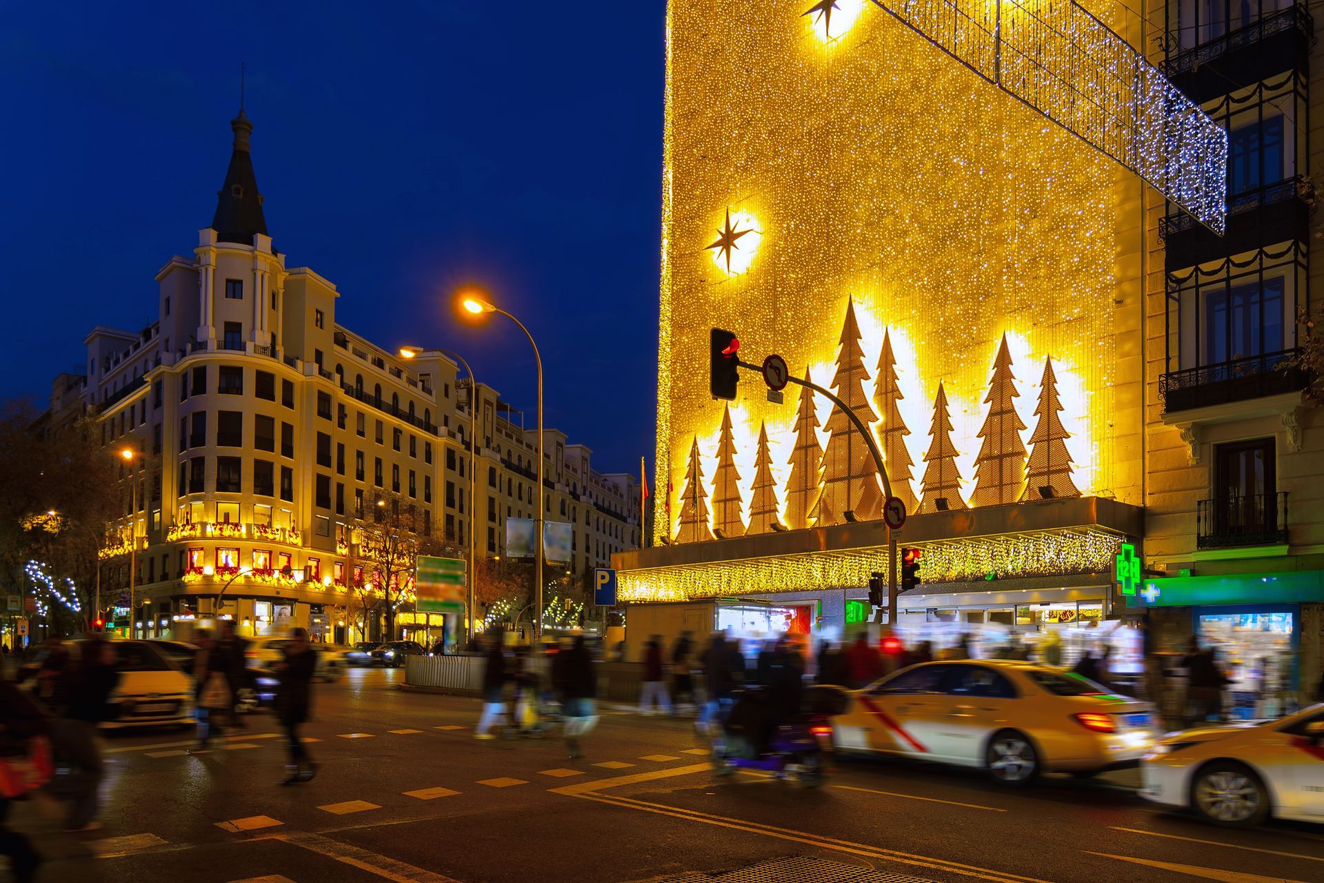 Night scene: Street in Madrid, Spain, with Christmas lights, buildings, cars, and pedestrians.