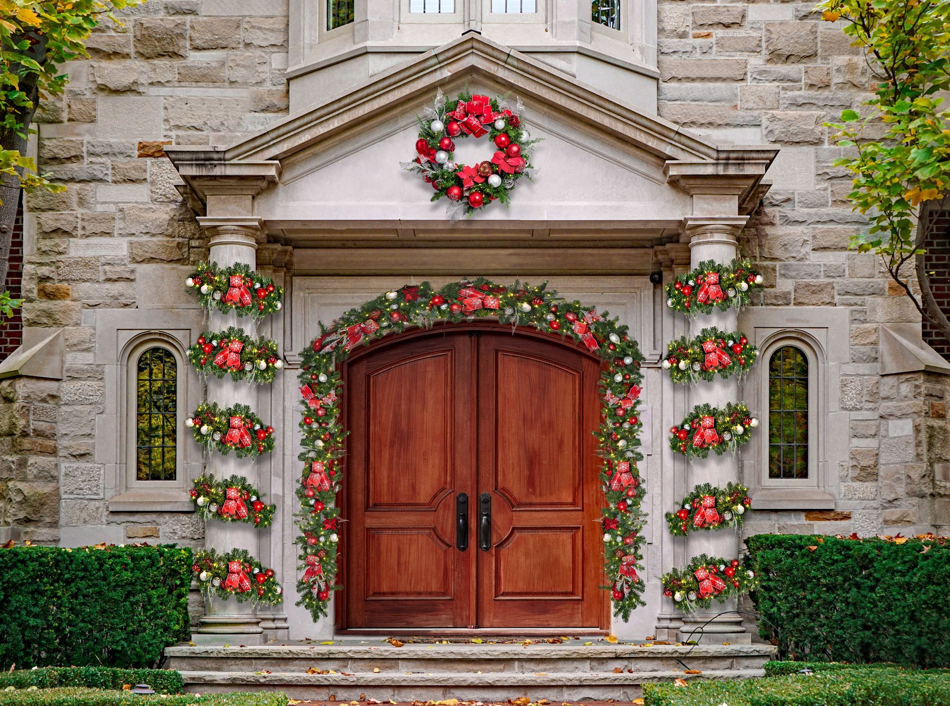 Ornate stone building entrance decorated with Christmas garlands and wreaths; wooden doors.