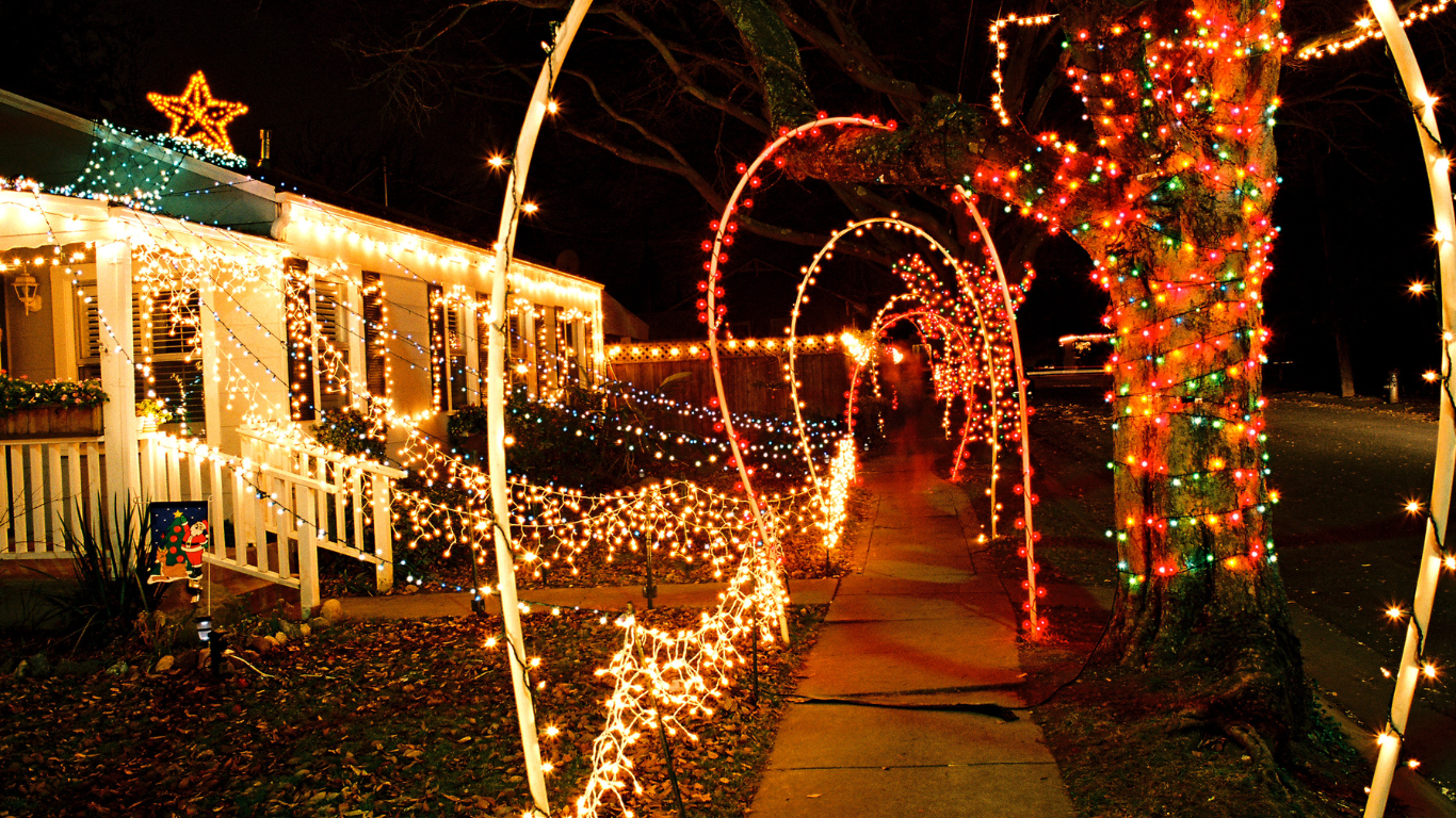 House and sidewalk decorated with Christmas lights at night.