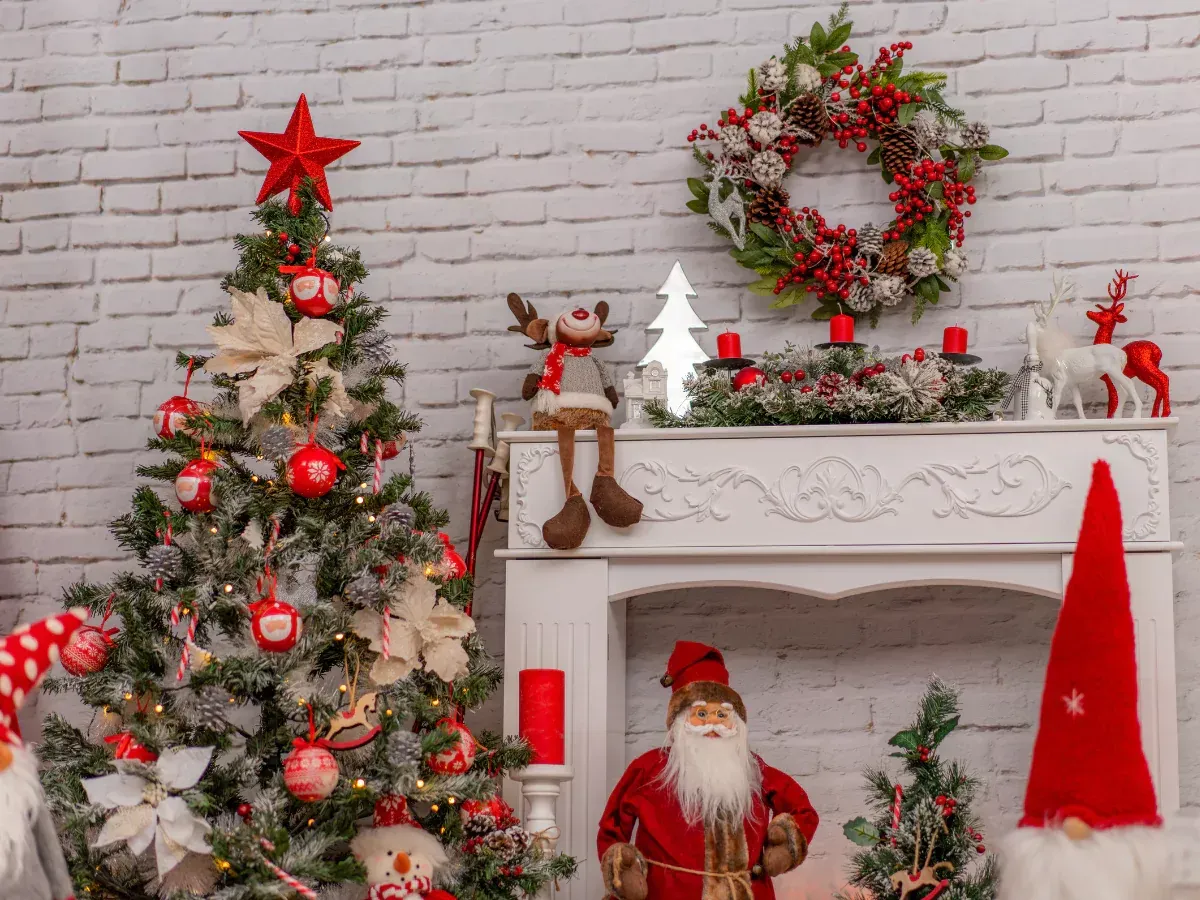 Christmas scene: decorated tree, fireplace with wreath, Santa, and festive decorations against a white brick wall.