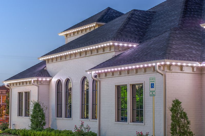 A large white house with christmas lights on the side of it.