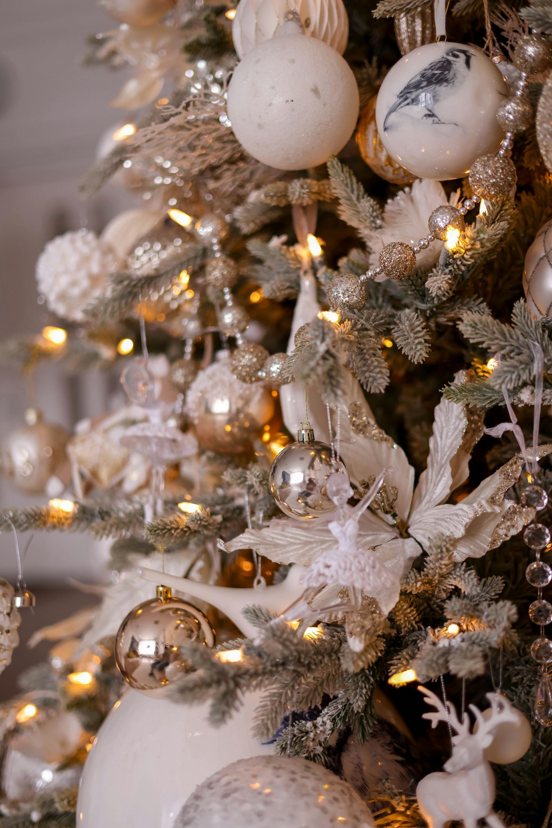 Close-up of decorated Christmas tree with white, gold, and silver ornaments and lights.