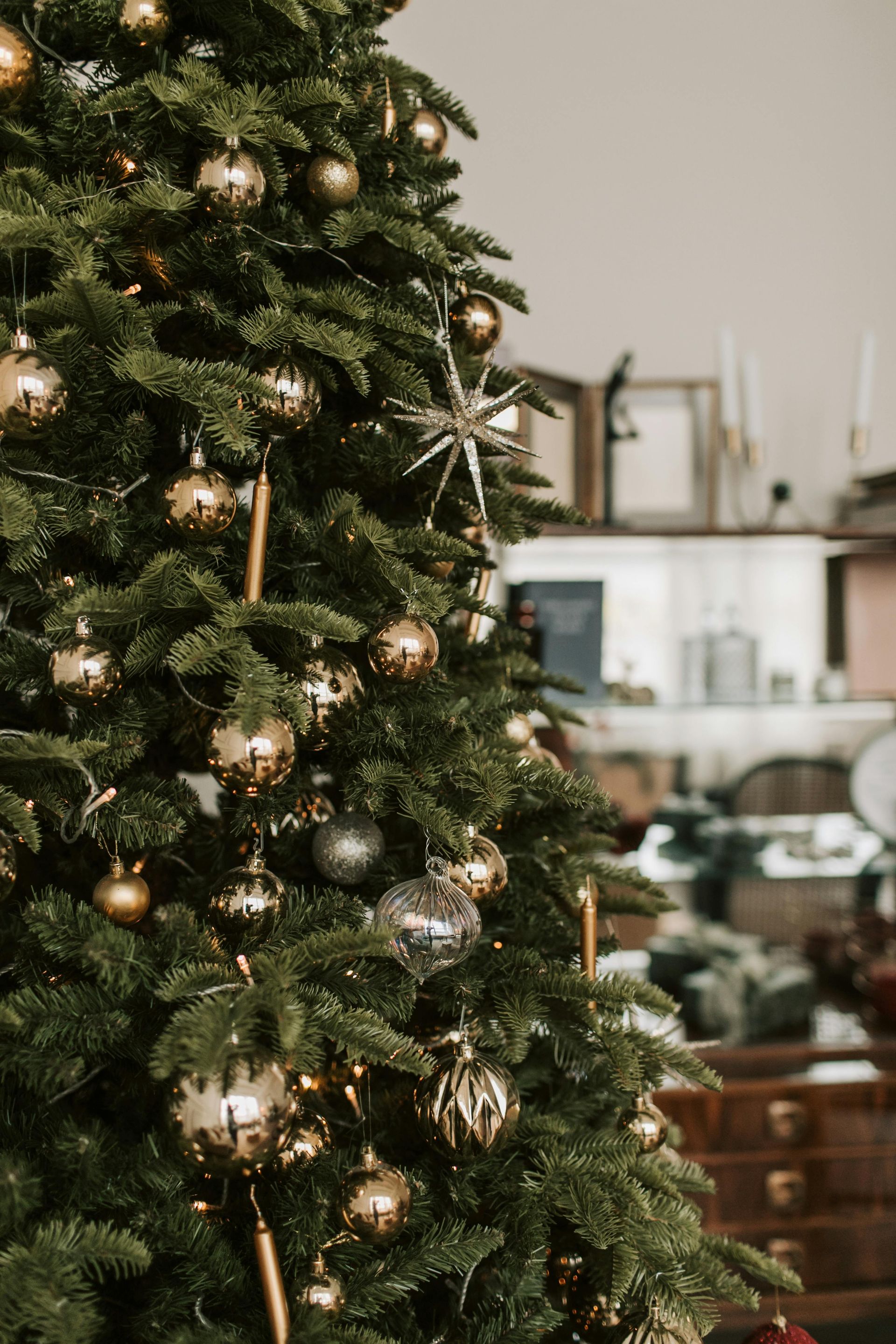 A christmas tree is decorated with gold balls and a star.