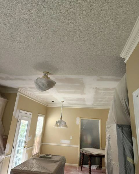 A kitchen ceiling with a popcorn texture, partially sanded, with covered furniture and light fixtures.