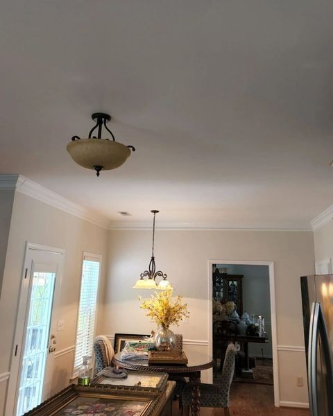 Dining room with two chandeliers, table, chairs, and doorway to another room.