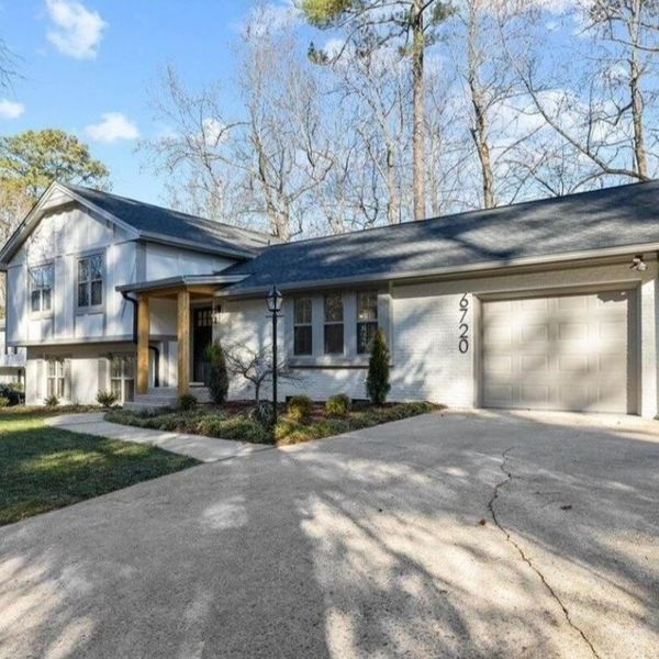 Gray house with a garage, driveway, and lawn. Number 958 is visible on the garage. Trees in the background.