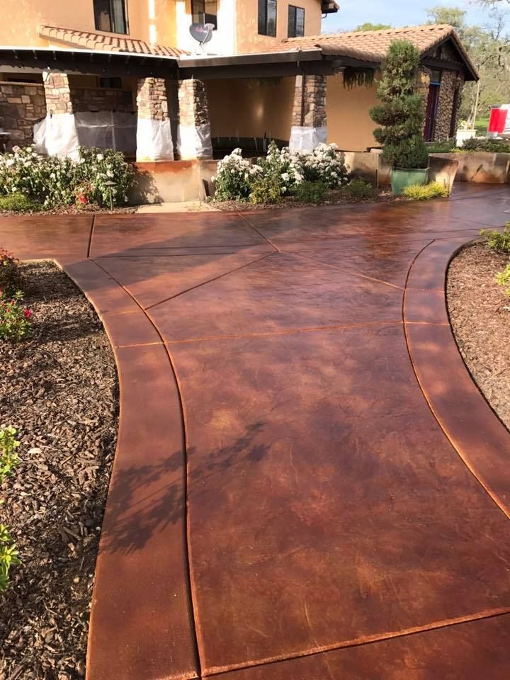A stained concrete walkway leading to a house.
