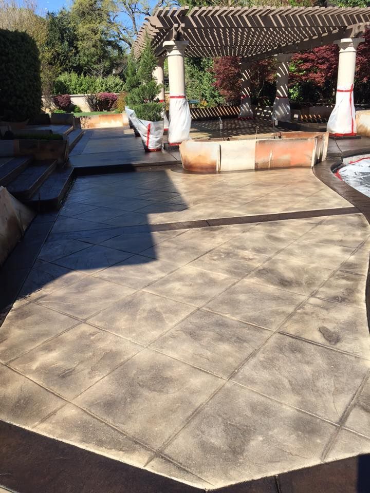 A patio with a pergola and a hot tub in the background.