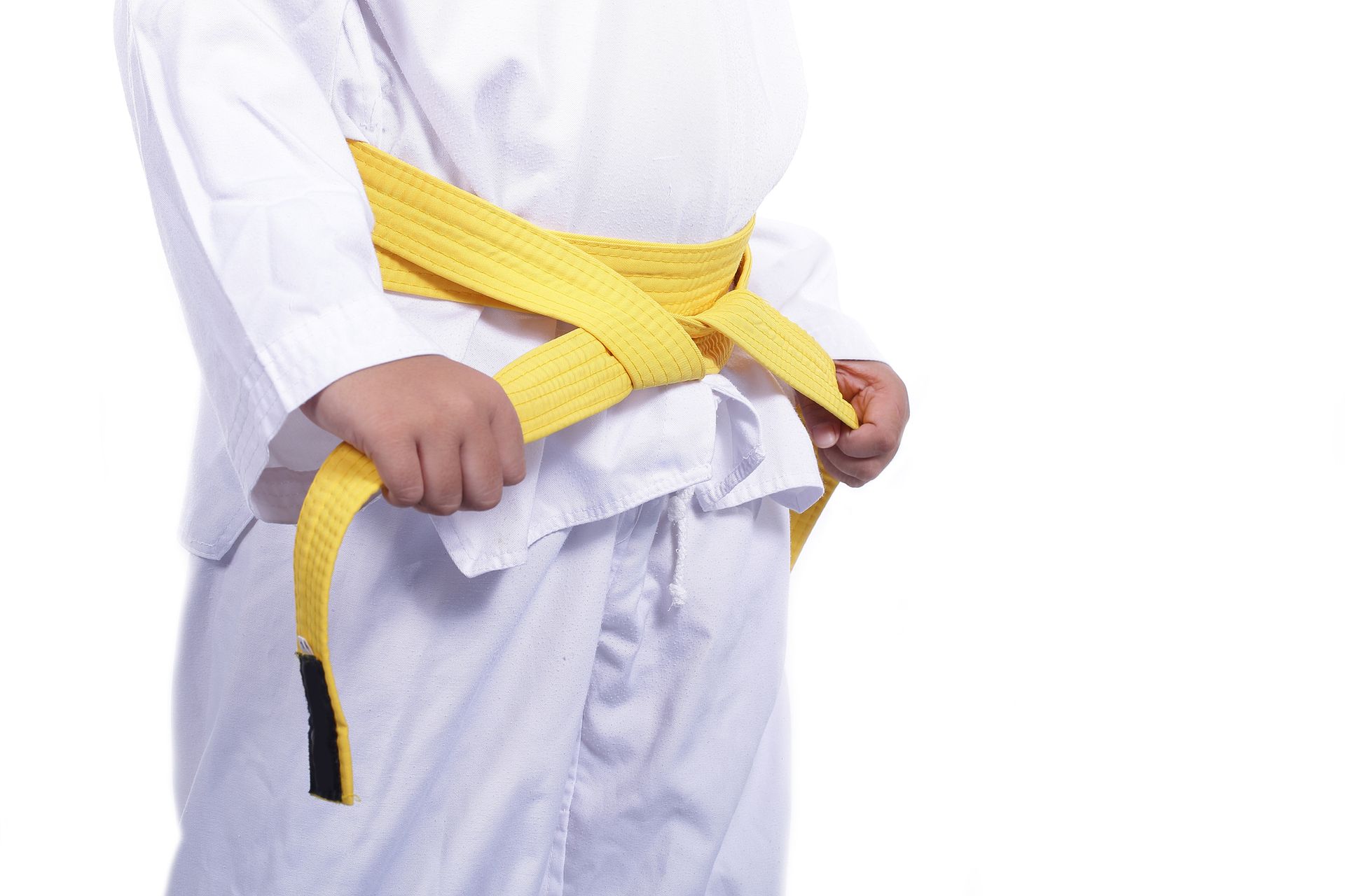 Child in white martial arts uniform tying a yellow belt. Child in white martial arts uniform tying a yellow belt.