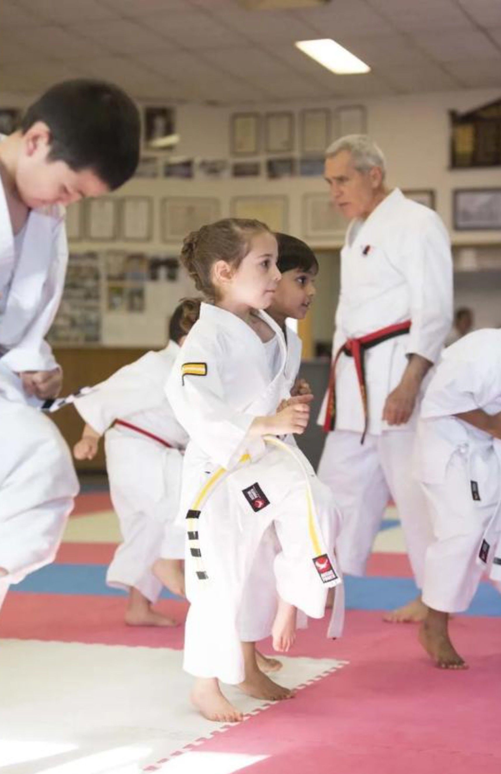 Group of students practicing martial arts in a dojo wearing white uniforms.