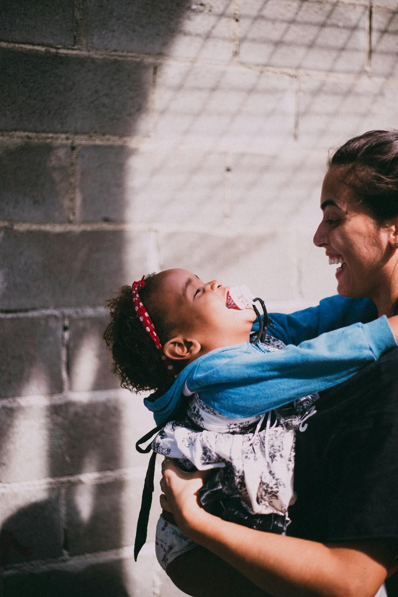 A woman is holding a baby in her arms and the baby is laughing.
