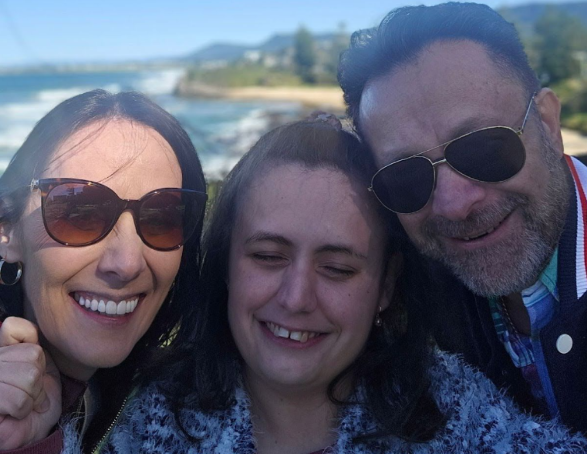 Two women holding a young woman with disabilities on the beach