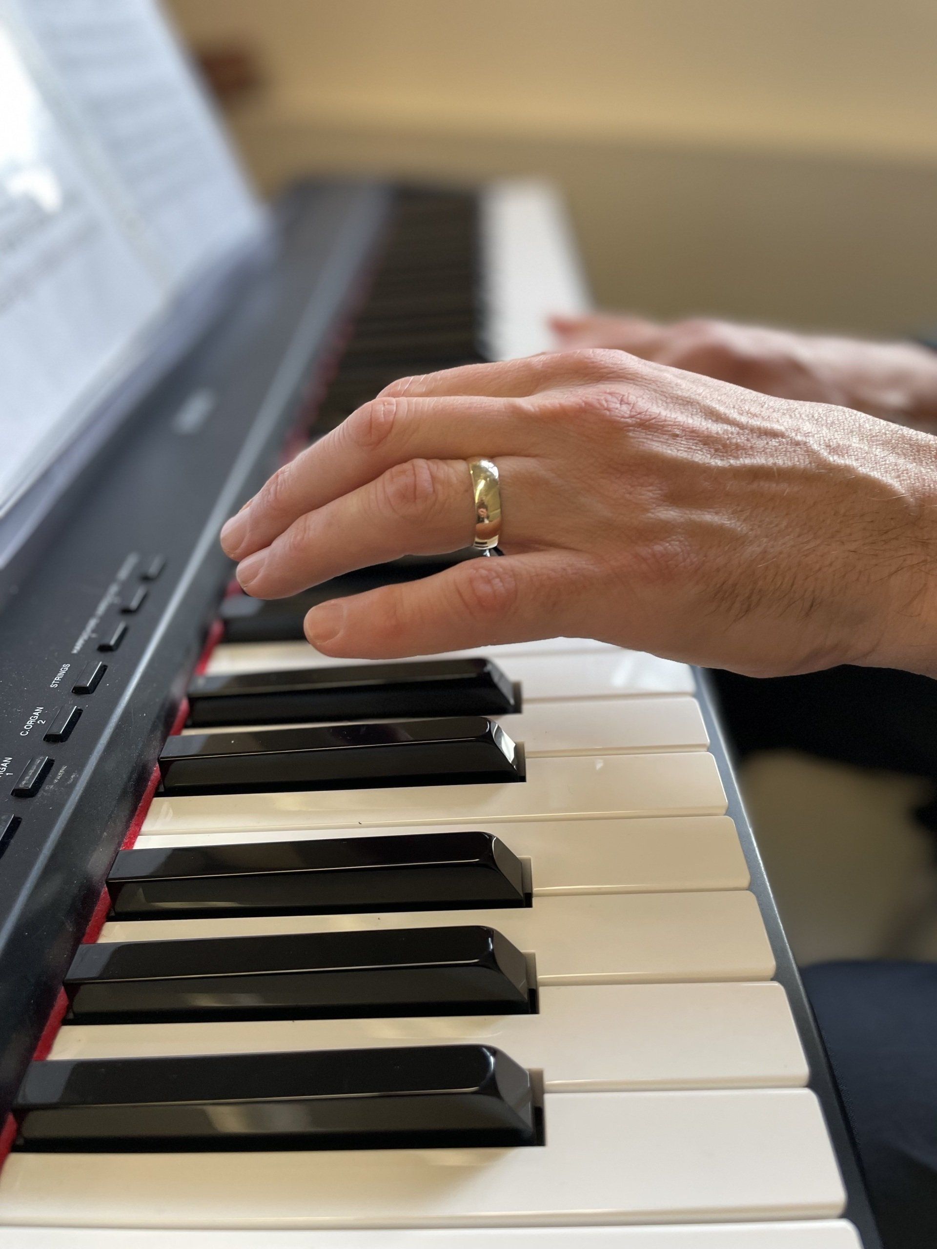 A person with a ring on their finger is playing a piano