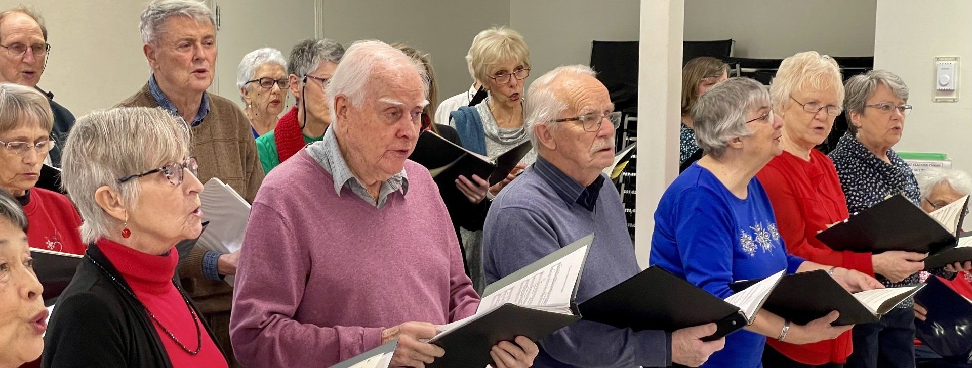 A group of elderly people are singing in a choir.