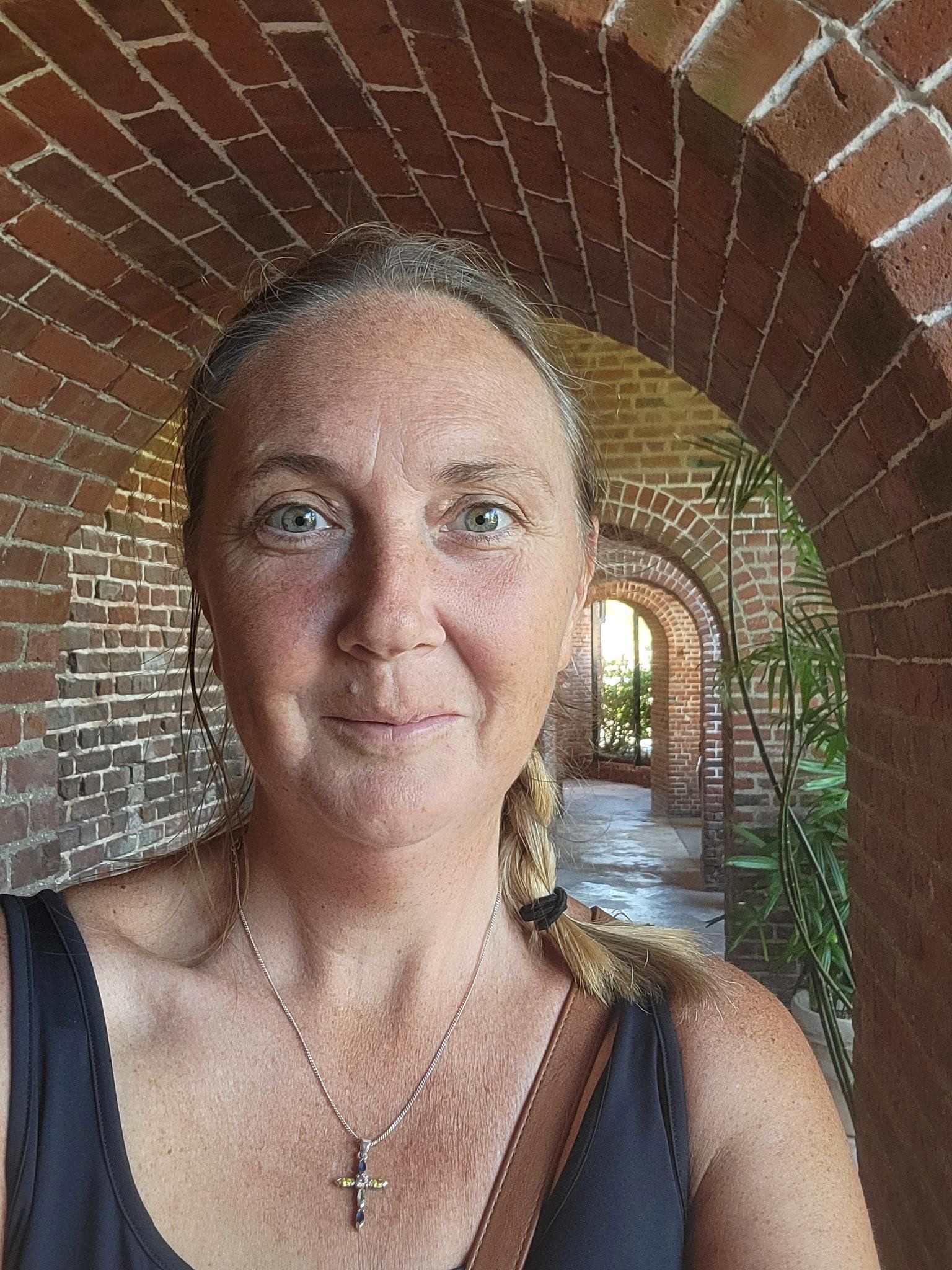 Woman smiling wearing black and white striped shirt with blue background