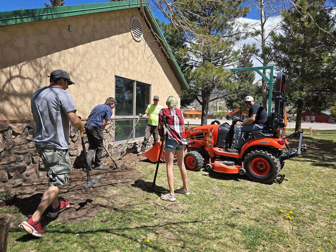 A group of people are working in a yard next to a tractor.