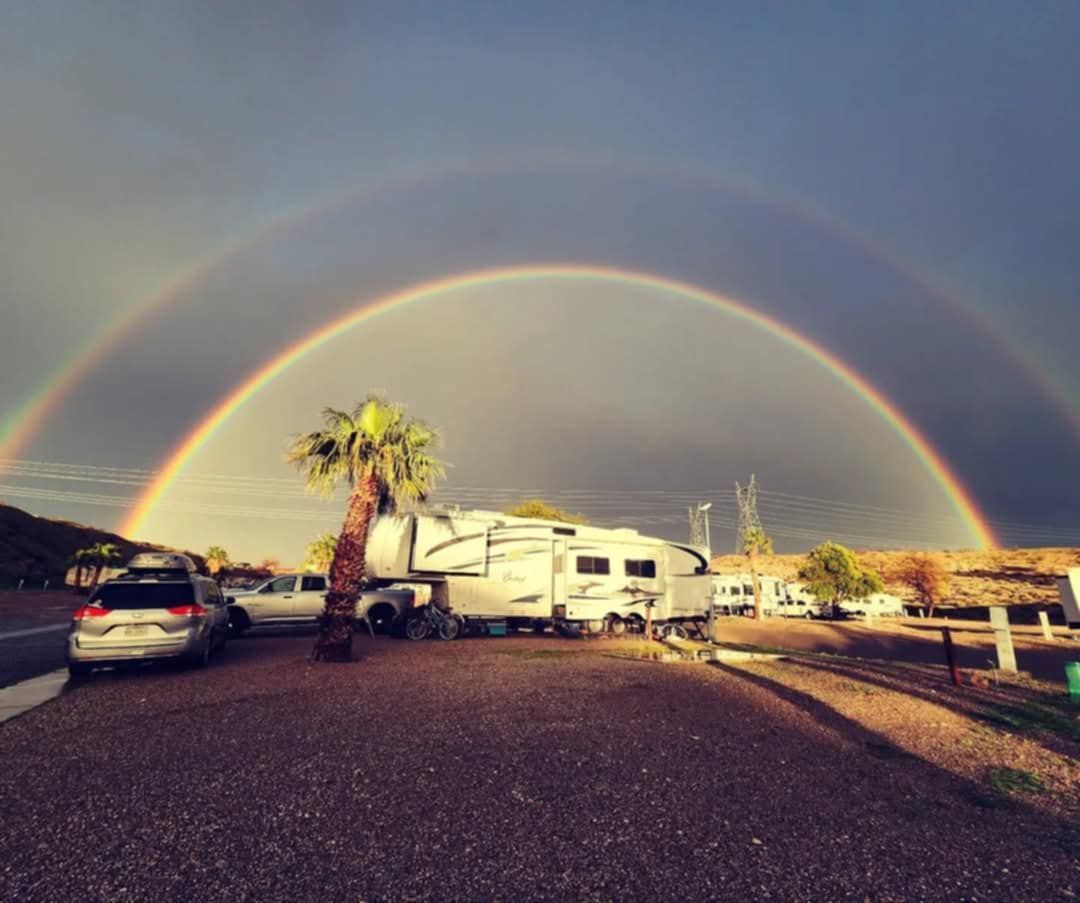 There is a double rainbow in the sky over a rv park.