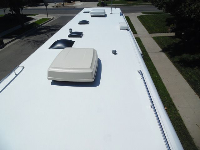 The roof of a white bus with a few vents on it