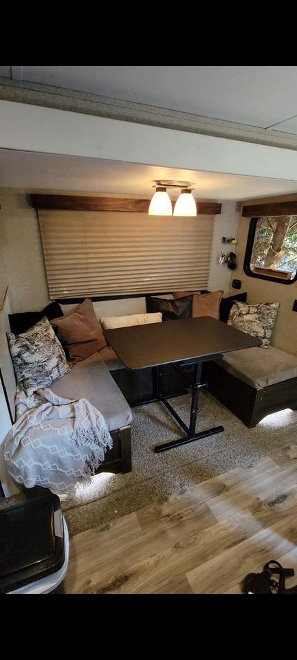 Interior of RV with a dark brown table and U-shaped seating area with pillows.